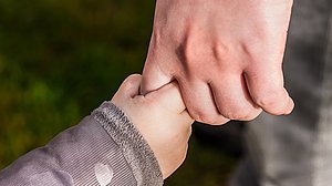 Hand eines kleinen Kindes umfasst den Zeigefinger eines Erwachsenen